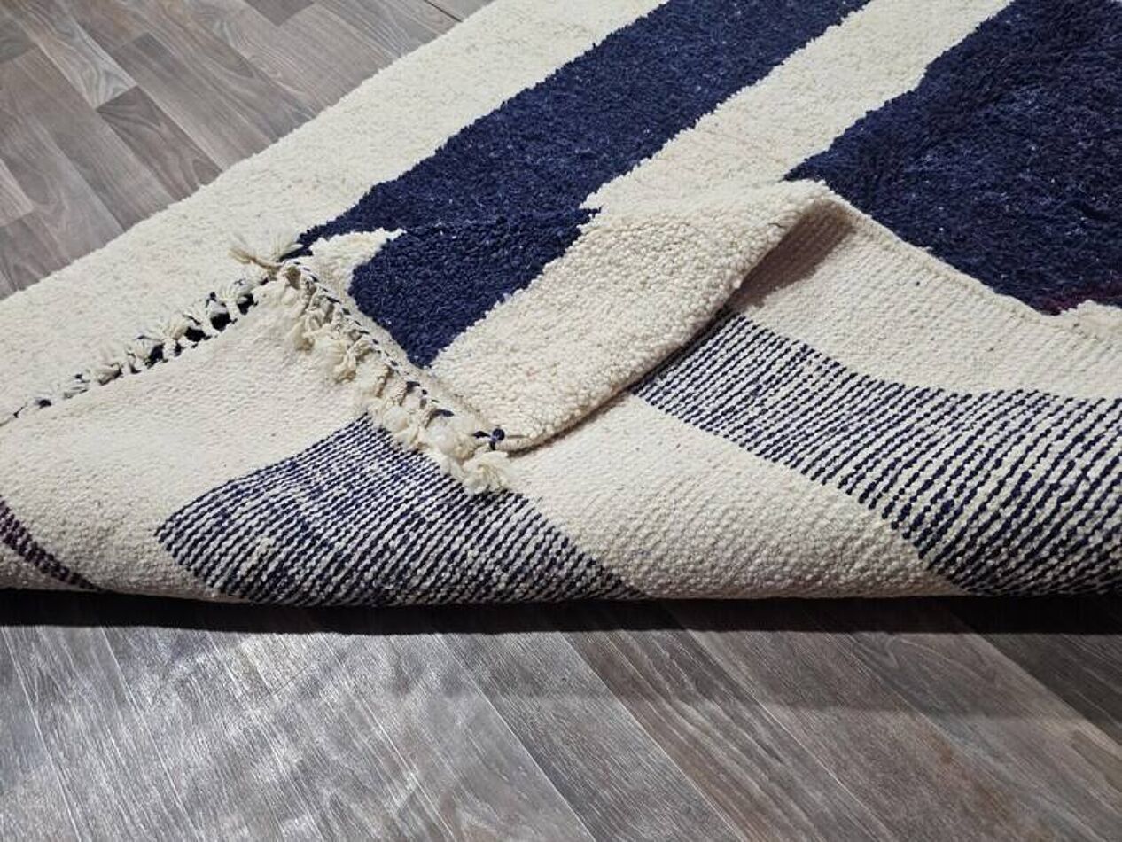Navy and beige checkered rug on a wooden floor