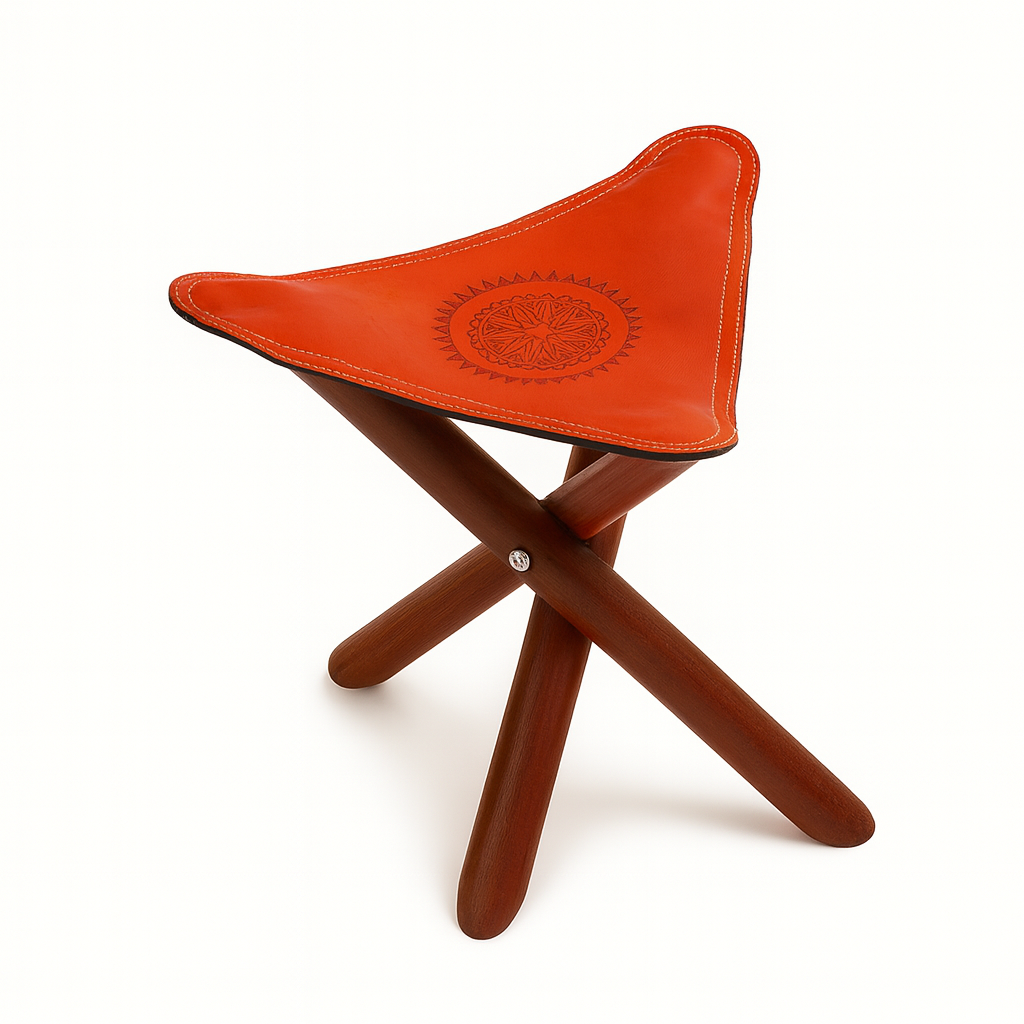 Moroccan leather tripod stool with embossed tan leather seat and wooden foldable legs, handcrafted by artisans in Morocco.
