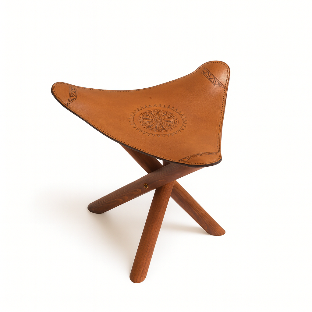 Handcrafted Moroccan stool with ocher leather seat and dark wooden tripod legs inspired by nomadic craftsmanship.
