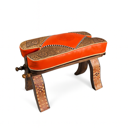 Handcrafted Moroccan stool with vibrant orange embossed leather cushion, carved wooden base, and inlaid mosaic details; measures 20.5 x 7.9 x 12.2 inches.
