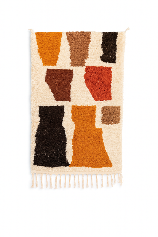 Handwoven Beni Ourain mini rug with warm earth toned geometric block shapes on an ivory wool background.
