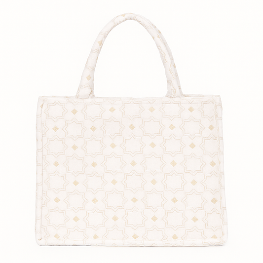 Ivory Moroccan brocade tote with geometric star motifs and short padded handles, featuring a structured silhouette and soft golden accents.
