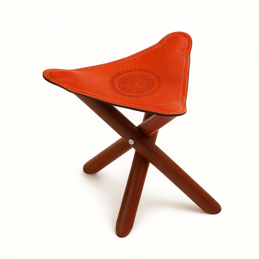 Moroccan leather tripod stool with embossed tan leather seat and wooden foldable legs, handcrafted by artisans in Morocco.
