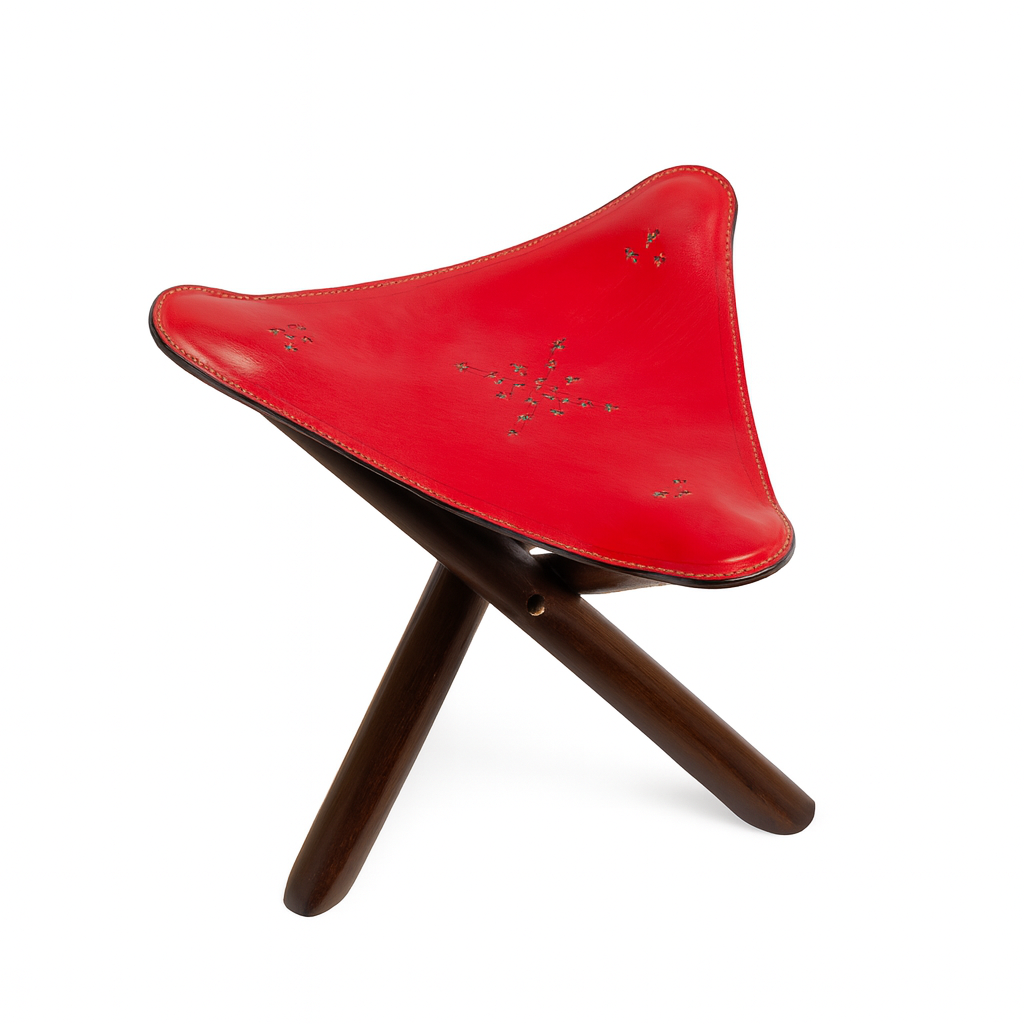 Handcrafted Moroccan stool with red leather triangular seat and dark wooden tripod base inspired by desert tones.
