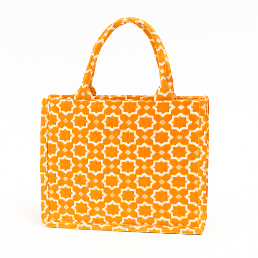 Structured Moroccan tote bag in tangerine orange velvet with ivory geometric star motifs and short padded handles, set against a white background.
